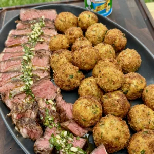 Different angle of plated ribeye slices with herb butter and golden croquettes, showing restaurant-quality presentation with seasoning bottle