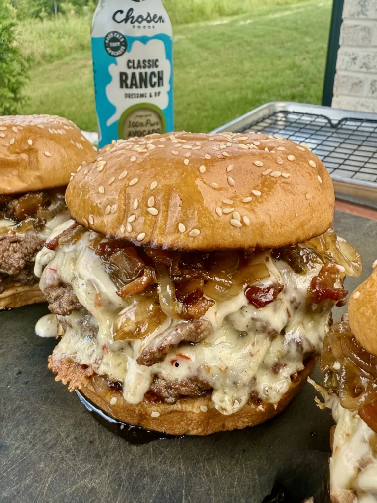 Three finished smash burgers side by side on dark slate surface with ranch dressing bottle, showing consistent results and restaurant-quality presentation
