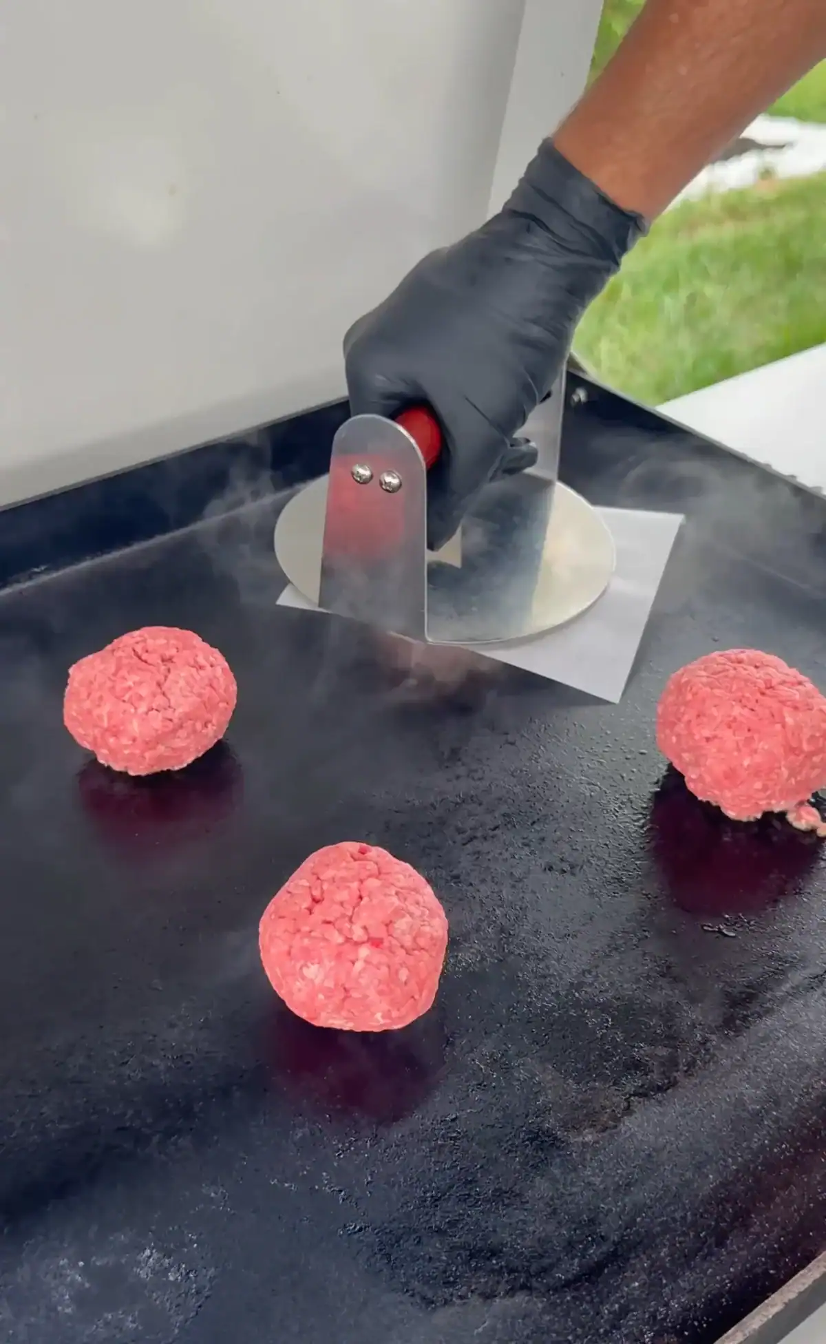 smash burger balls on the griddle being smashed
