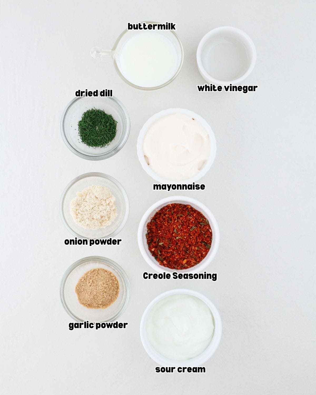 small bowls filled with ingredients for Creole ranch sauce, placed on a kitchen countertop.