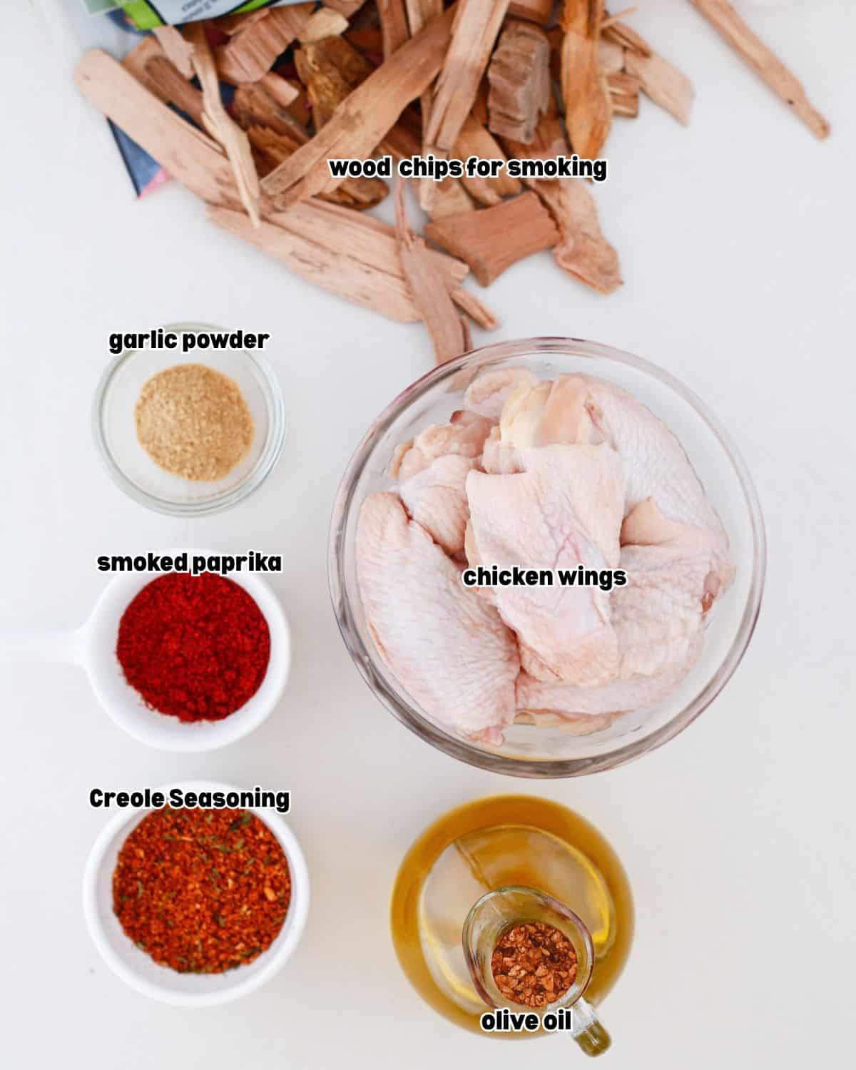ingredients for smoked and grilled Creole chicken wings placed in bowls on a flat kitchen countertop.