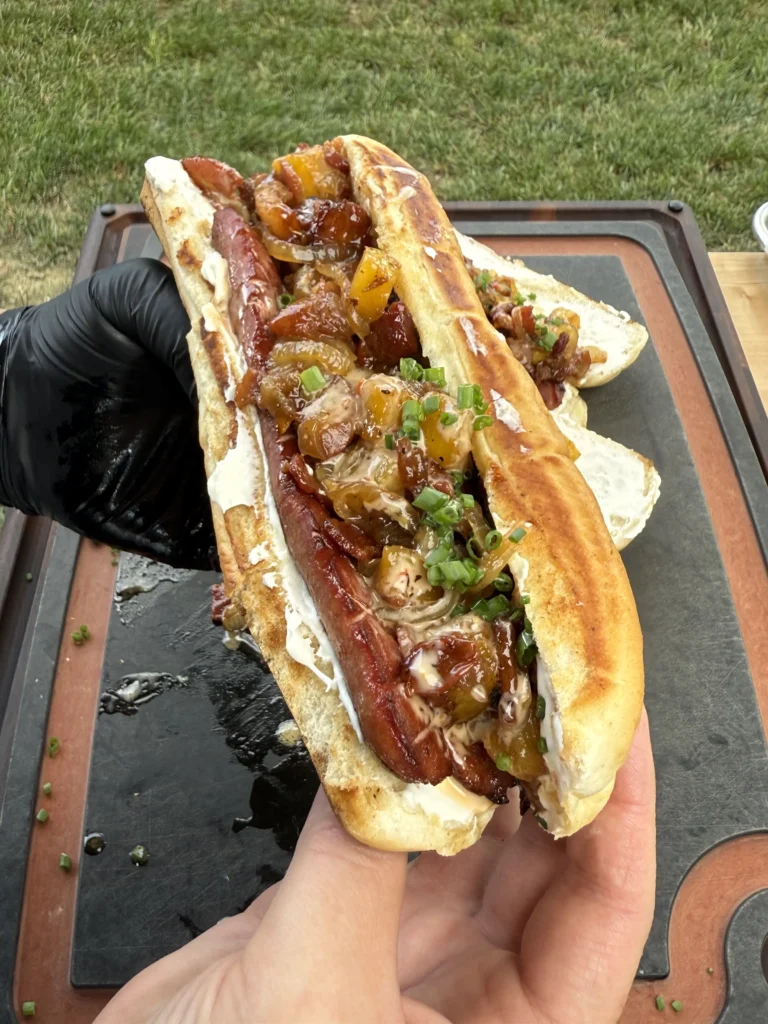 pineapple bacon jam hot dog being held vertically