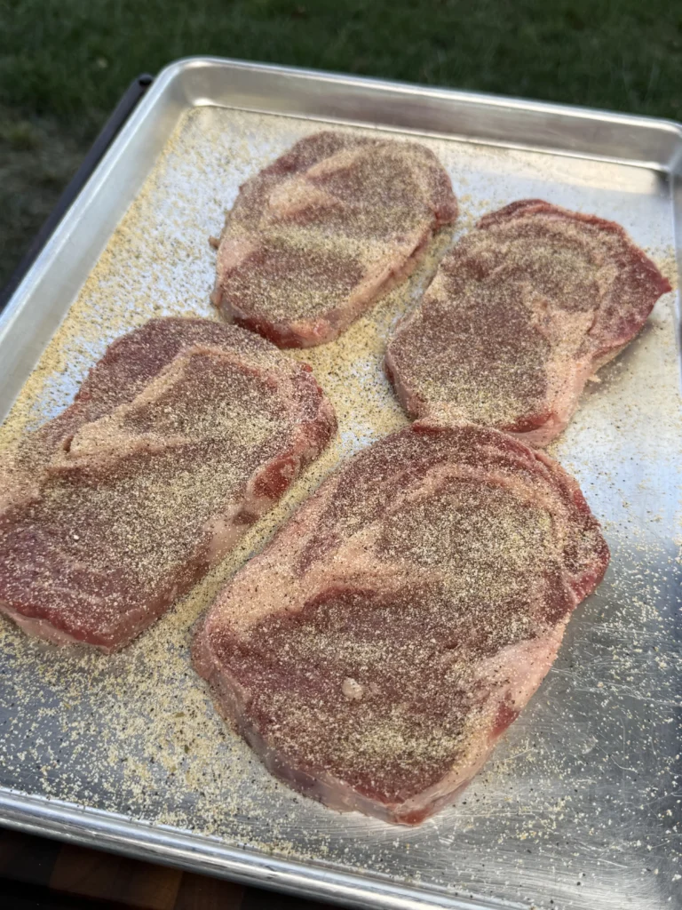 seasoned ribeye steaks for the sliders on a metal pan