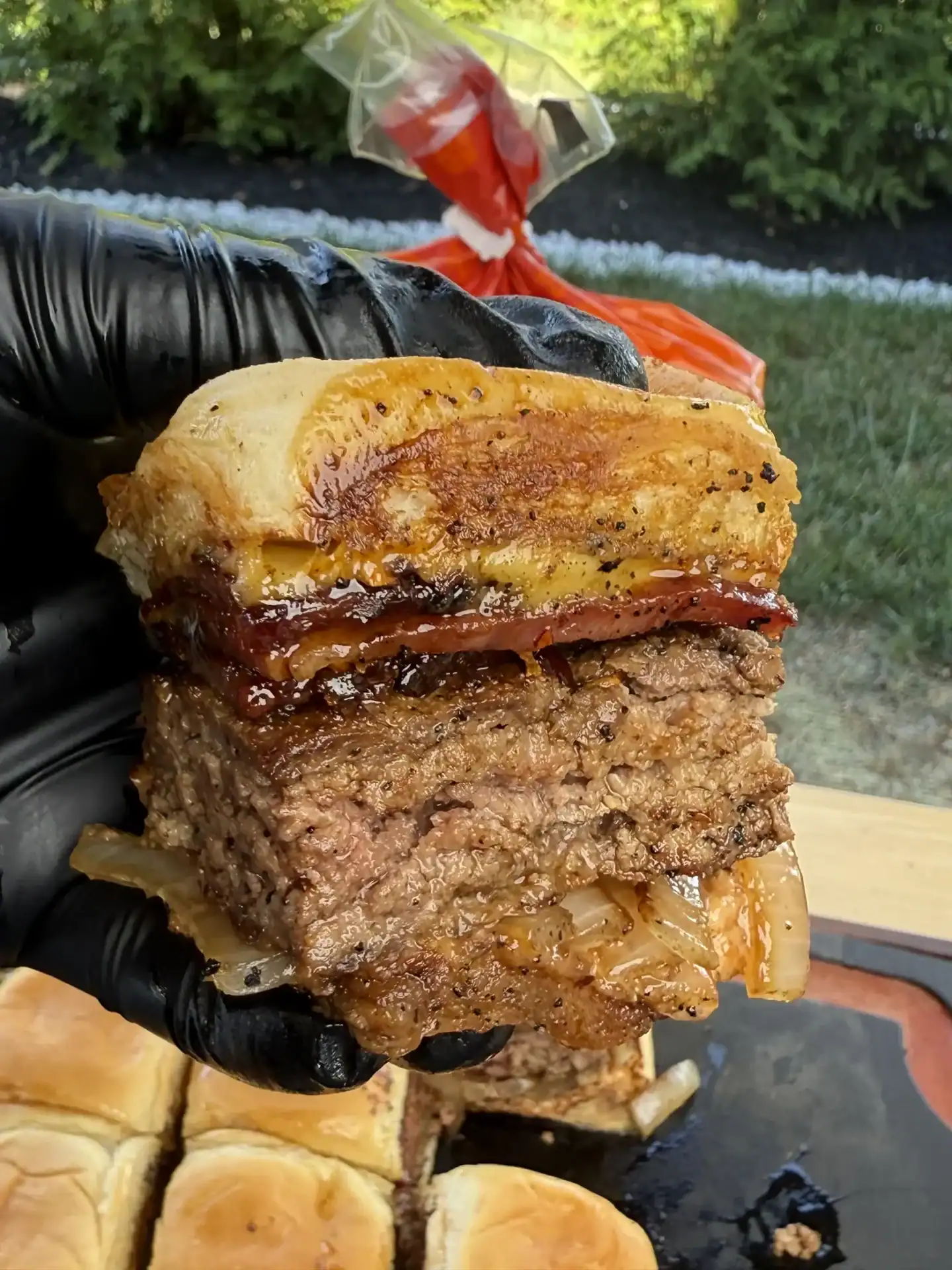 candied bacon slider being held up 