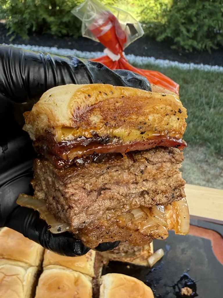 candied bacon slider being held up 