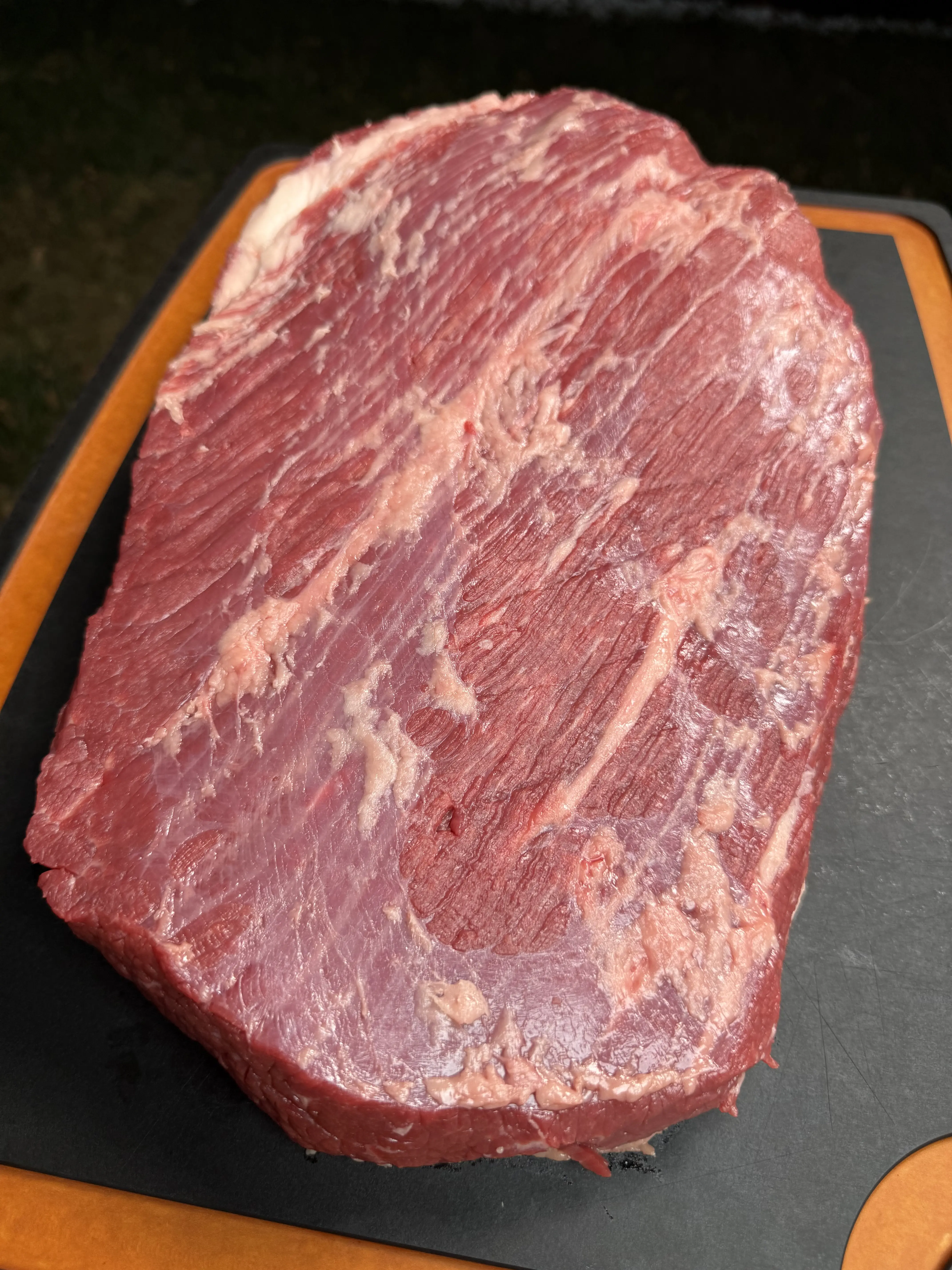 Trimmed brisket on a cutting board prepared for the pellet smoker