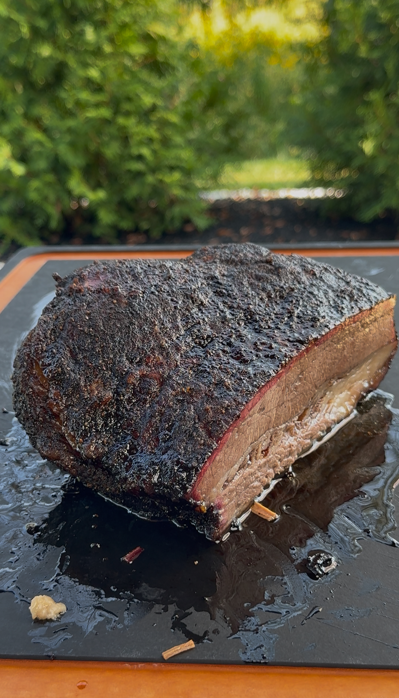 Sliced pellet smoked brisket on cutting board showing smoke ring