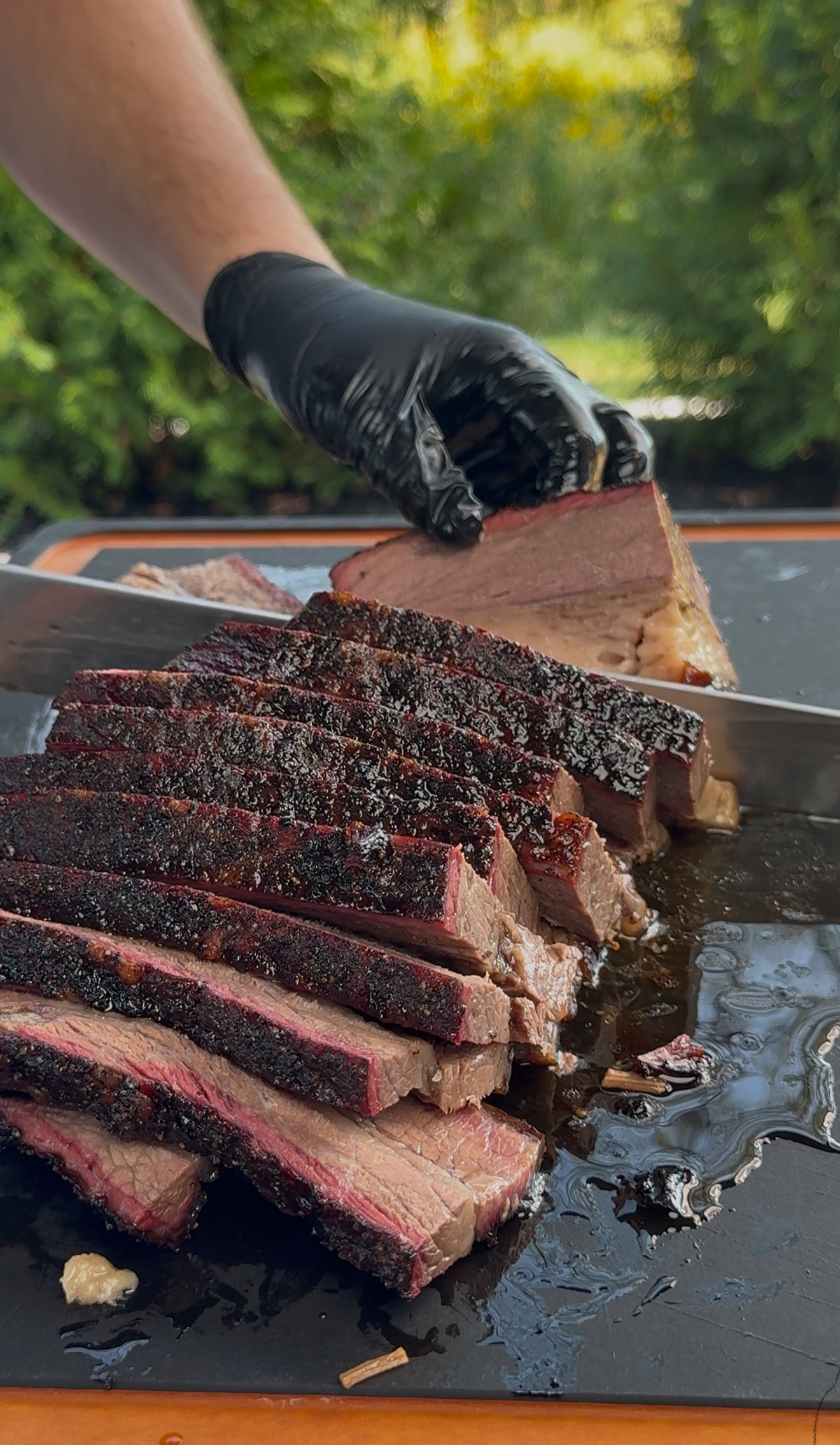 Sliced pellet smoked brisket on a cutting board showing smoke ring and juicy texture
