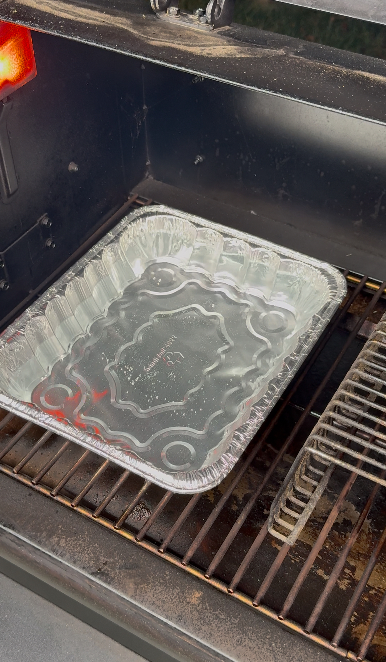 Water pan inside pellet smoker for humidity control during brisket cook