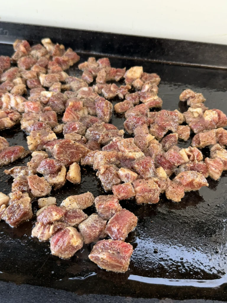 seasoned steak on the griddle