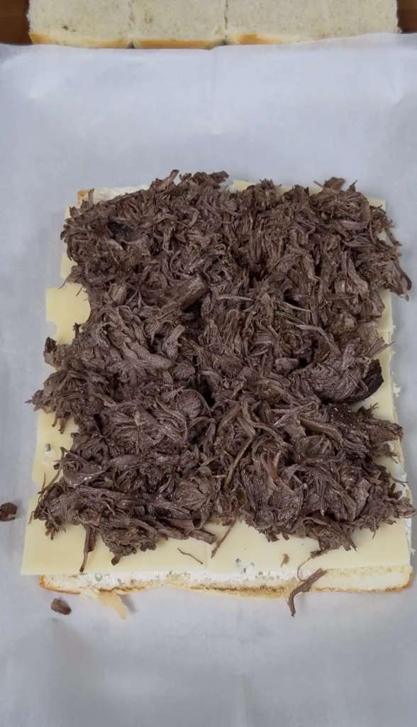 shredded beef on top of swiss cheese