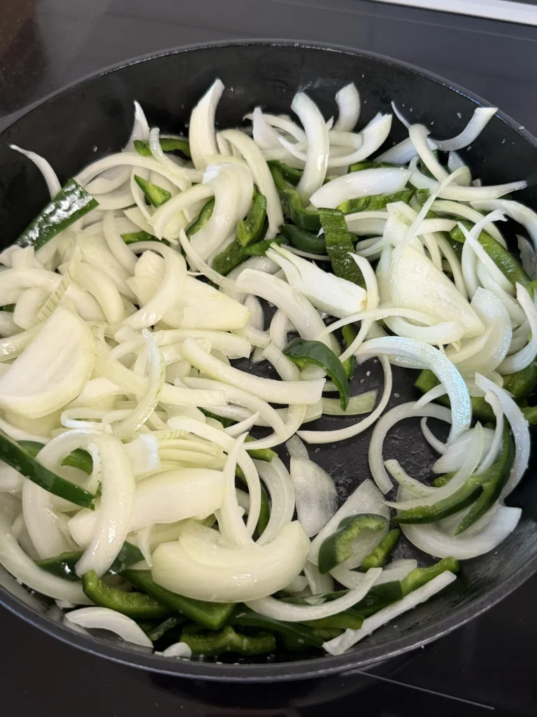 onions and bell peppers in a cast iron 