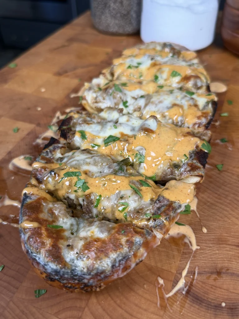 cheesesteak stuffed bread on a cutting board