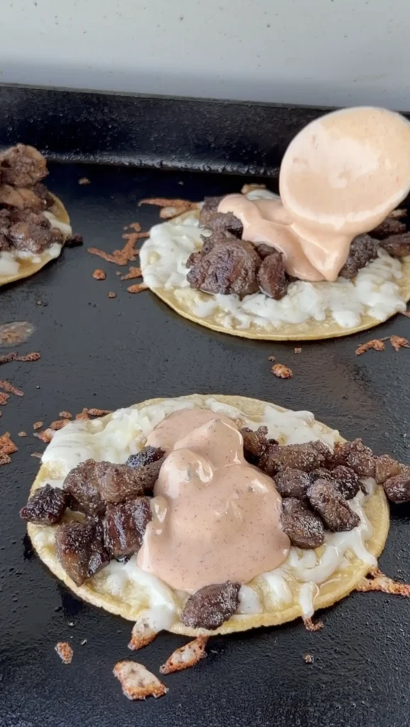 corn tortillas with meat and sauce on the griddle
