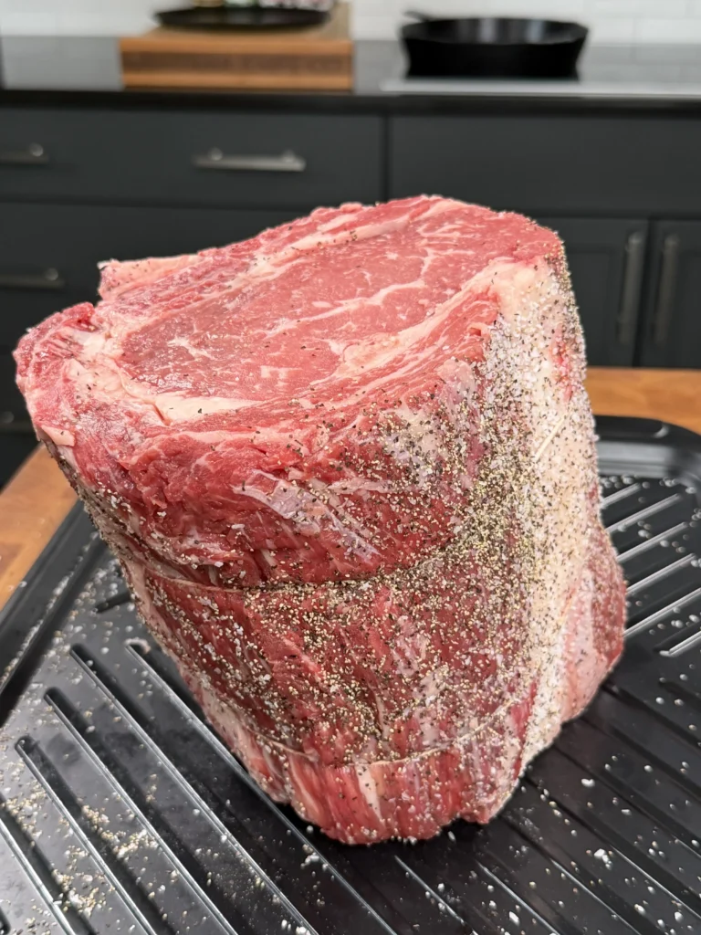 prepped prime rib on the cutting board with seasoning