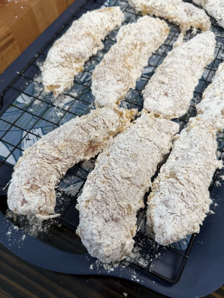 breaded chicken tenders sitting on a wire rack