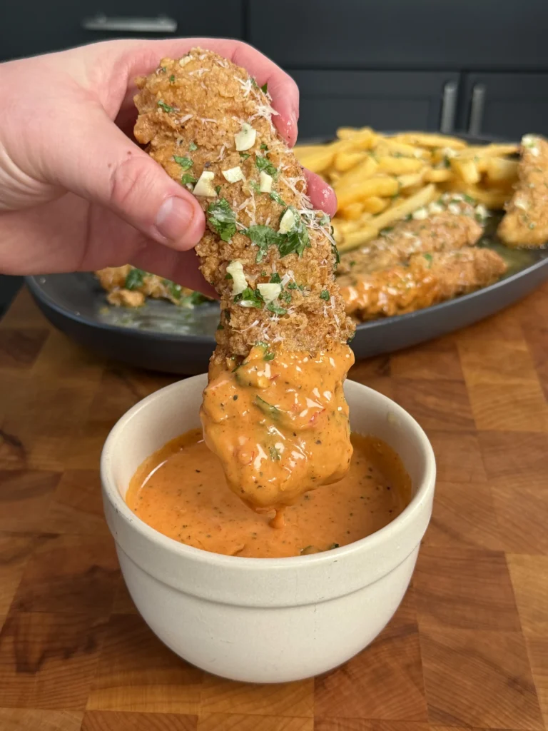 crispy chicken tenders being dipped in a sauce