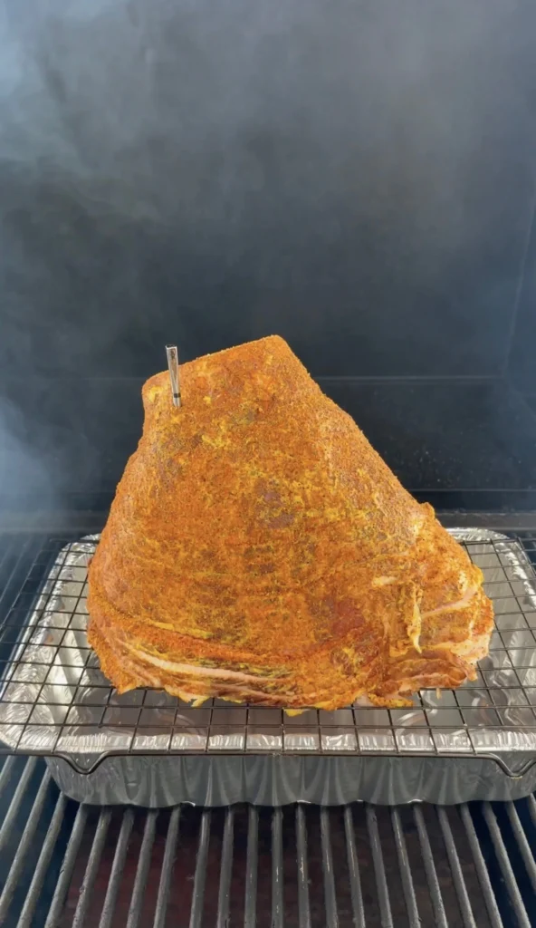 ham in the smoker with a metal pan beneath