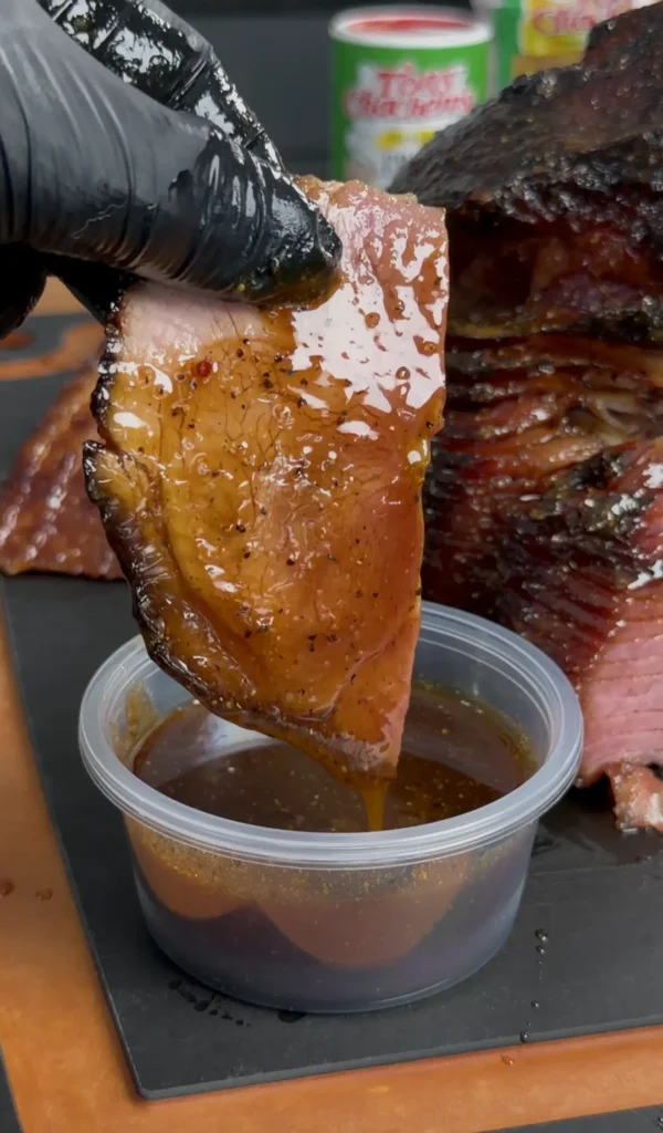sliced ham being dipped in the sauce