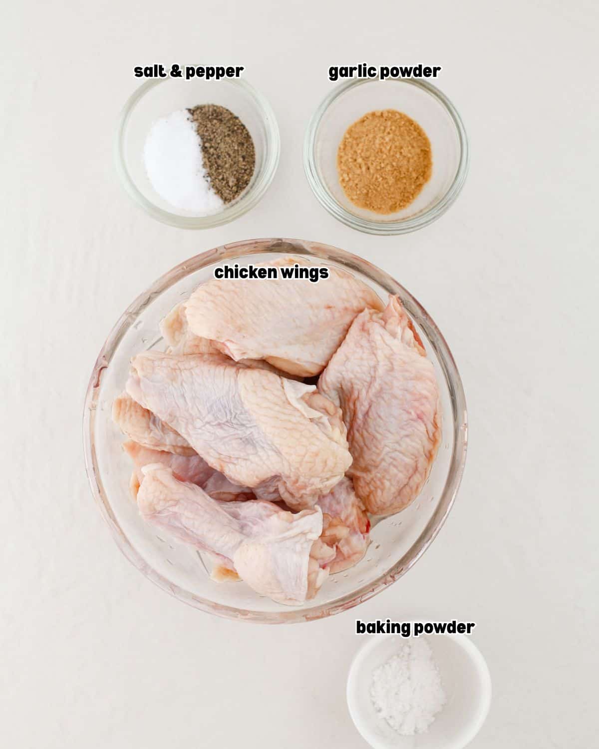 ingredients for honey garlic chicken wings placed in bowls on a clean kitchen countertop.