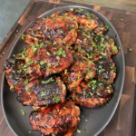 Close-up of crispy charred skin on a grilled chili lime chicken thigh showing golden caramelized edges