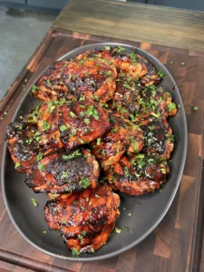 Close-up of crispy charred skin on a grilled chili lime chicken thigh showing golden caramelized edges