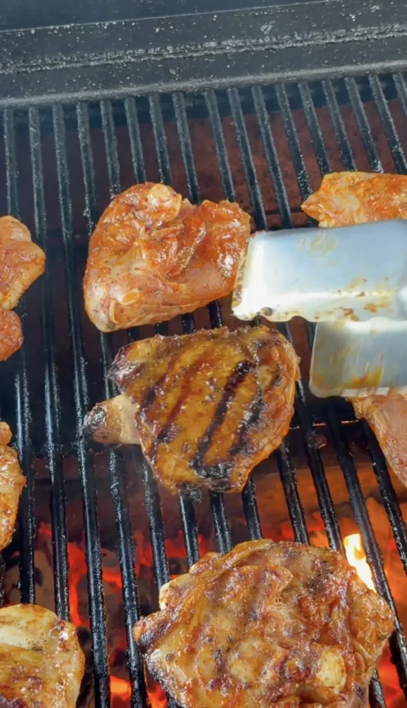 Chicken thighs finishing on the indirect heat side of a charcoal grill with lid open
