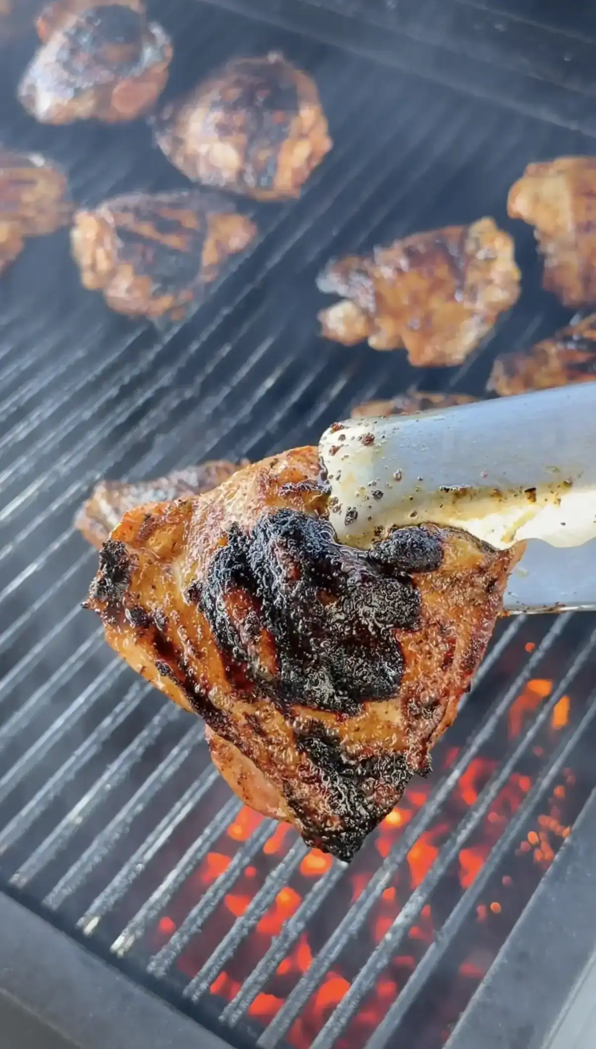 Chicken thighs finishing on the indirect heat side of a charcoal grill with lid open