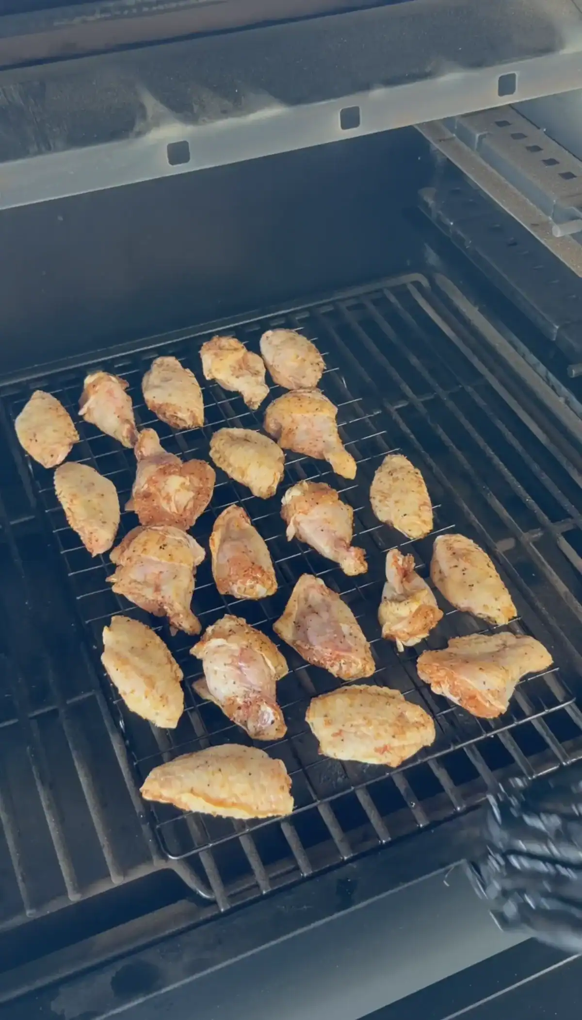 seasoned chicken wings placed in a single layer on a wire rack onto a pellet smoker.