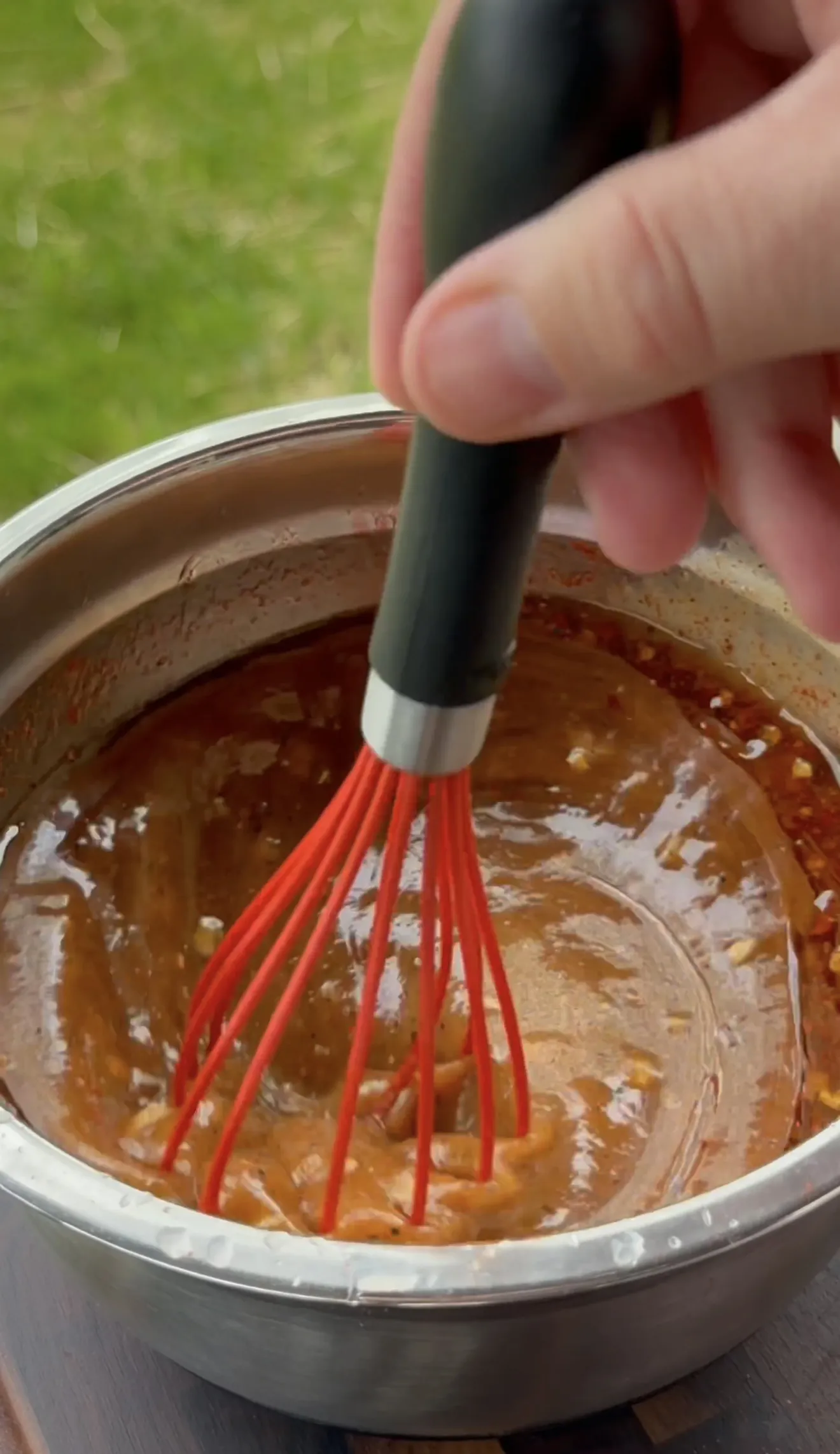 Whisking chicken marinade ingredients in a metal mixing bowl