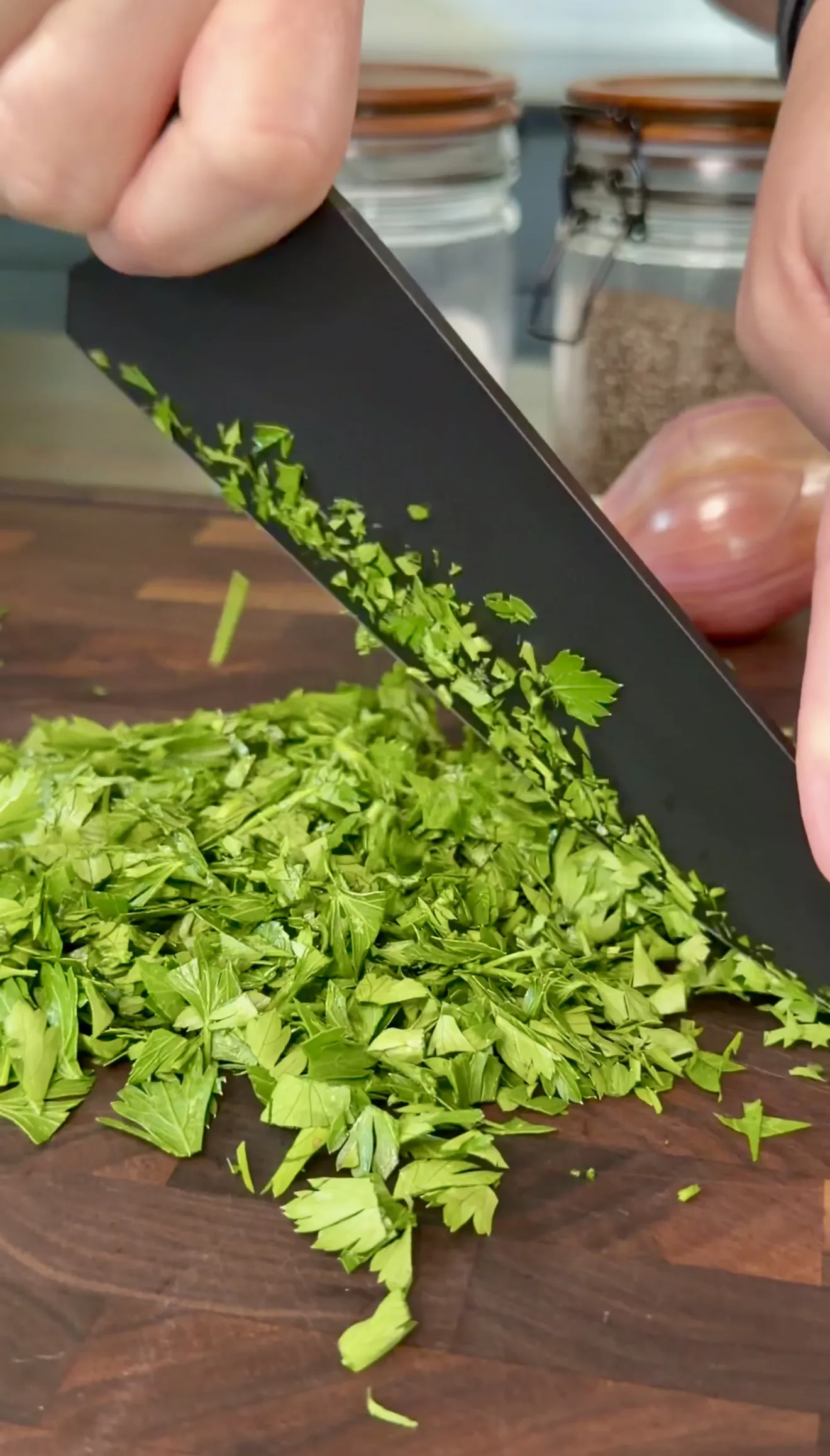 Chopping fresh parsley with a knife on a cutting board