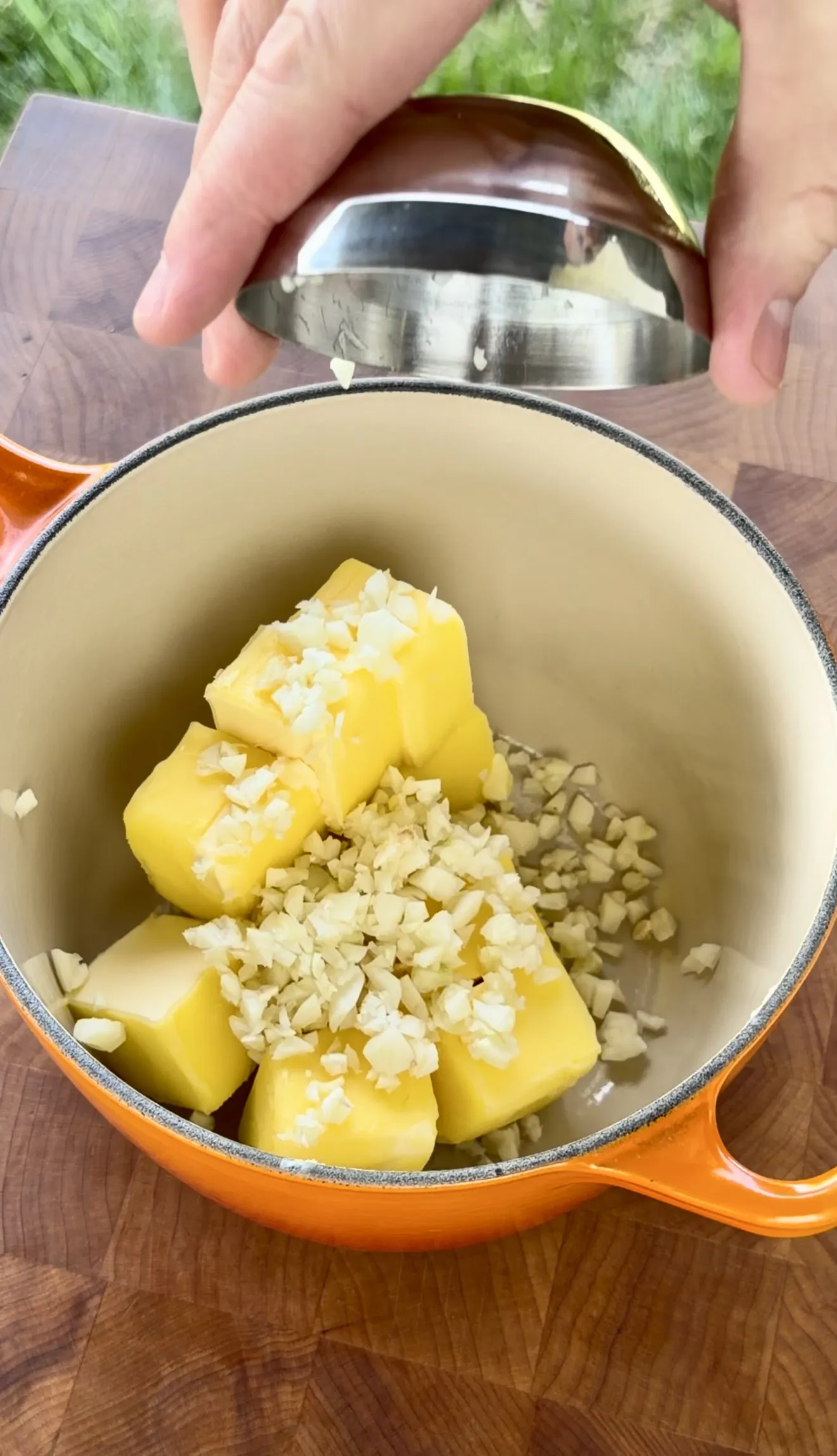 Garlic and butter cubes in an orange dutch oven for melting