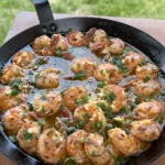 Golden seared shrimp with garlic butter and fresh herbs cooking in a black cast iron skillet