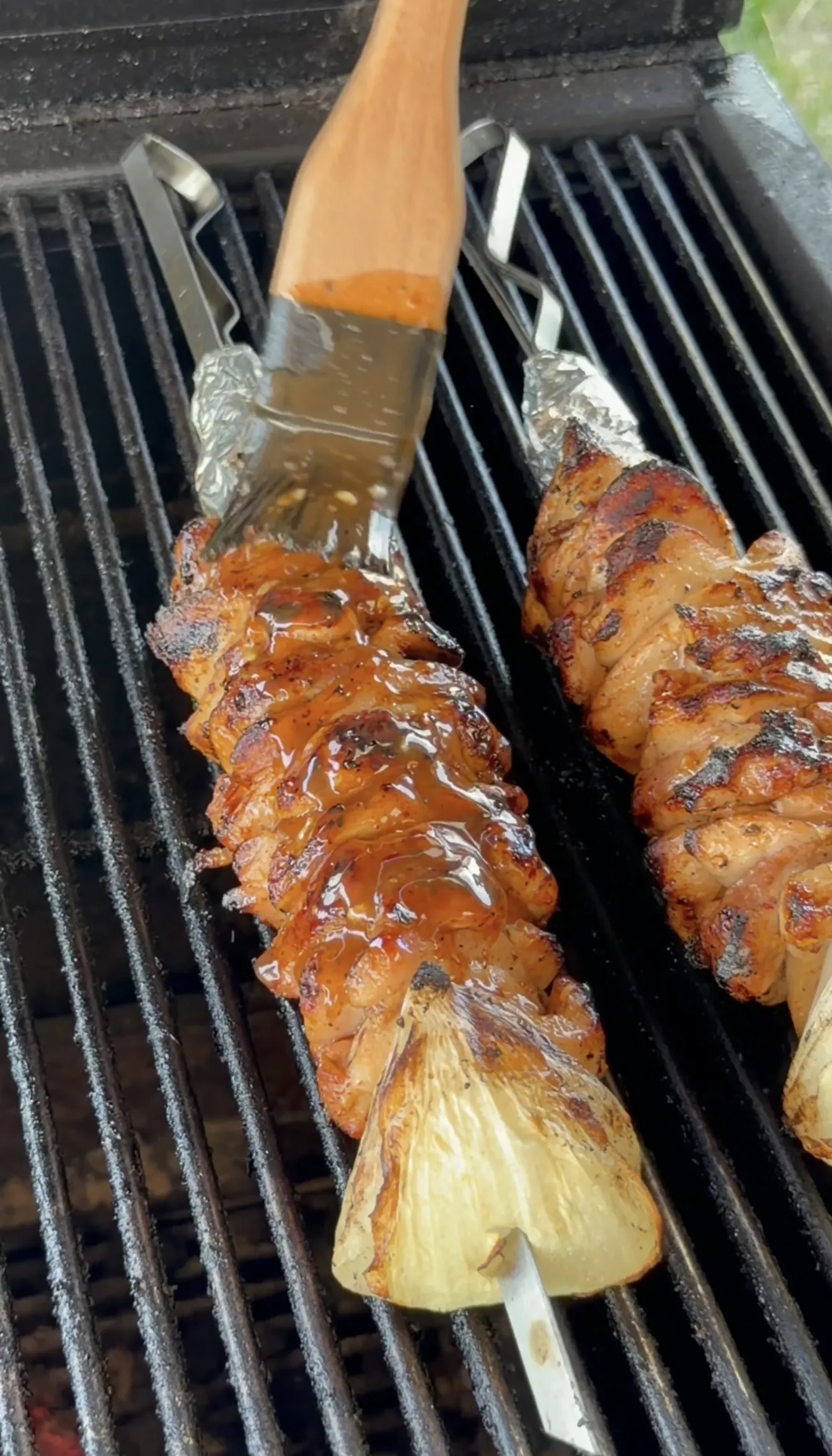 Threaded chicken skewers with onion chunks on the grill before cooking