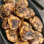 Golden brown honey chili crisp grilled chicken thighs with caramelized coating in a black skillet