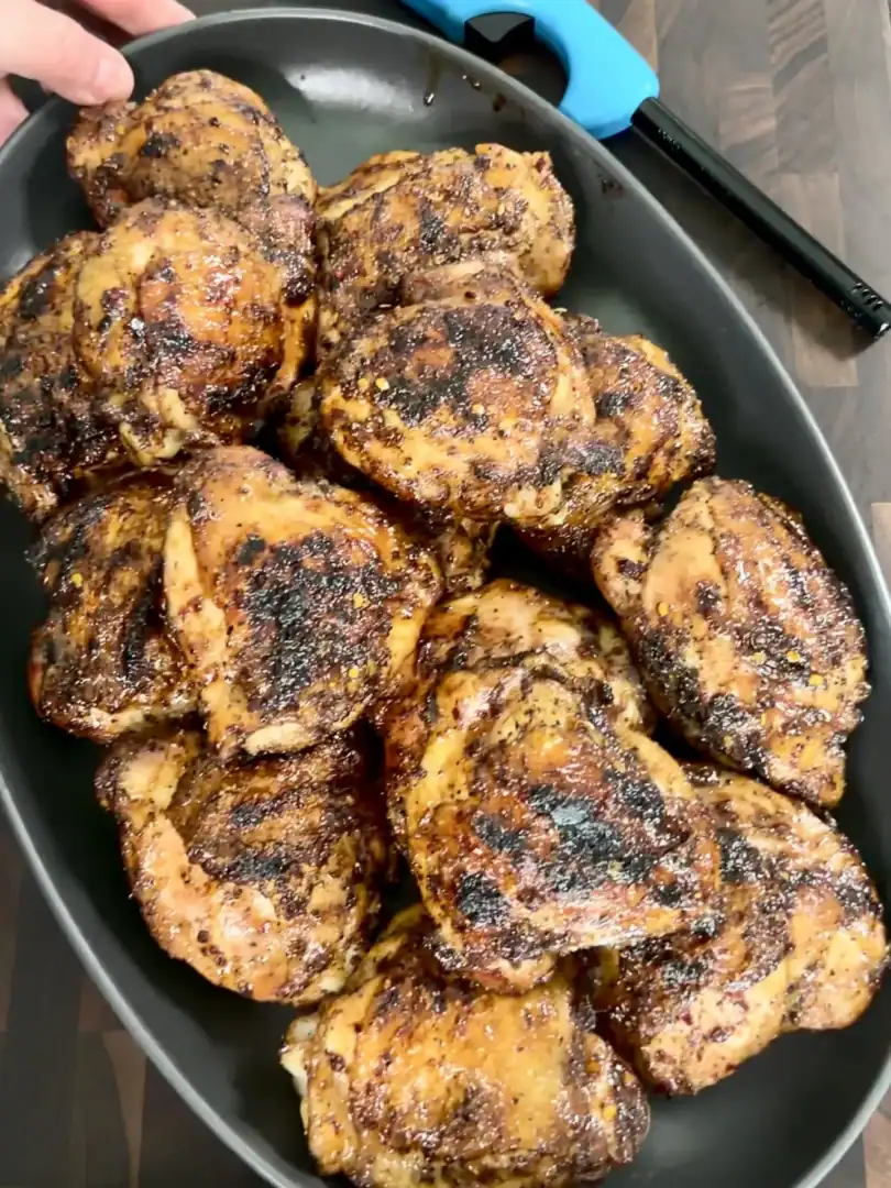 Golden brown honey chili crisp grilled chicken thighs with caramelized coating in a black skillet