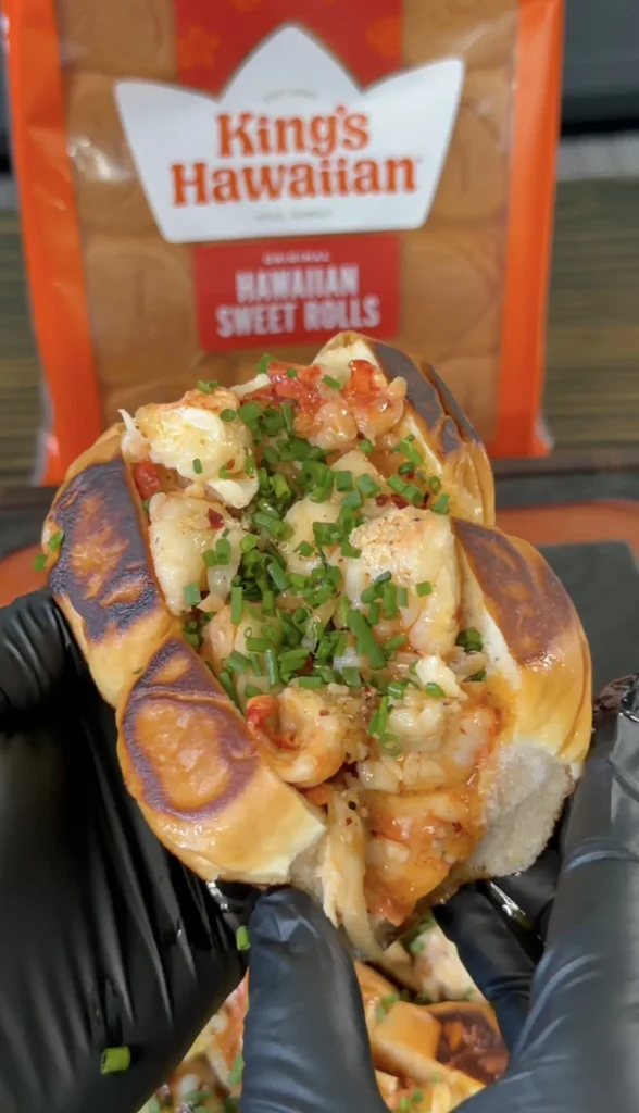 Hot honey butter lobster roll in toasted brioche bun topped with fresh chives and diced tomatoes