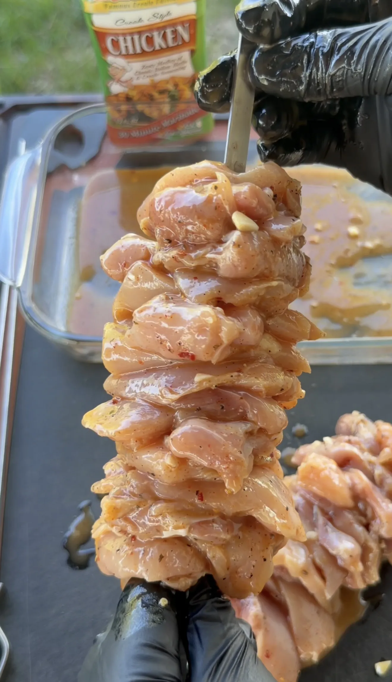 Boneless skinless chicken thighs marinating in a glass dish with lemon and garlic visible