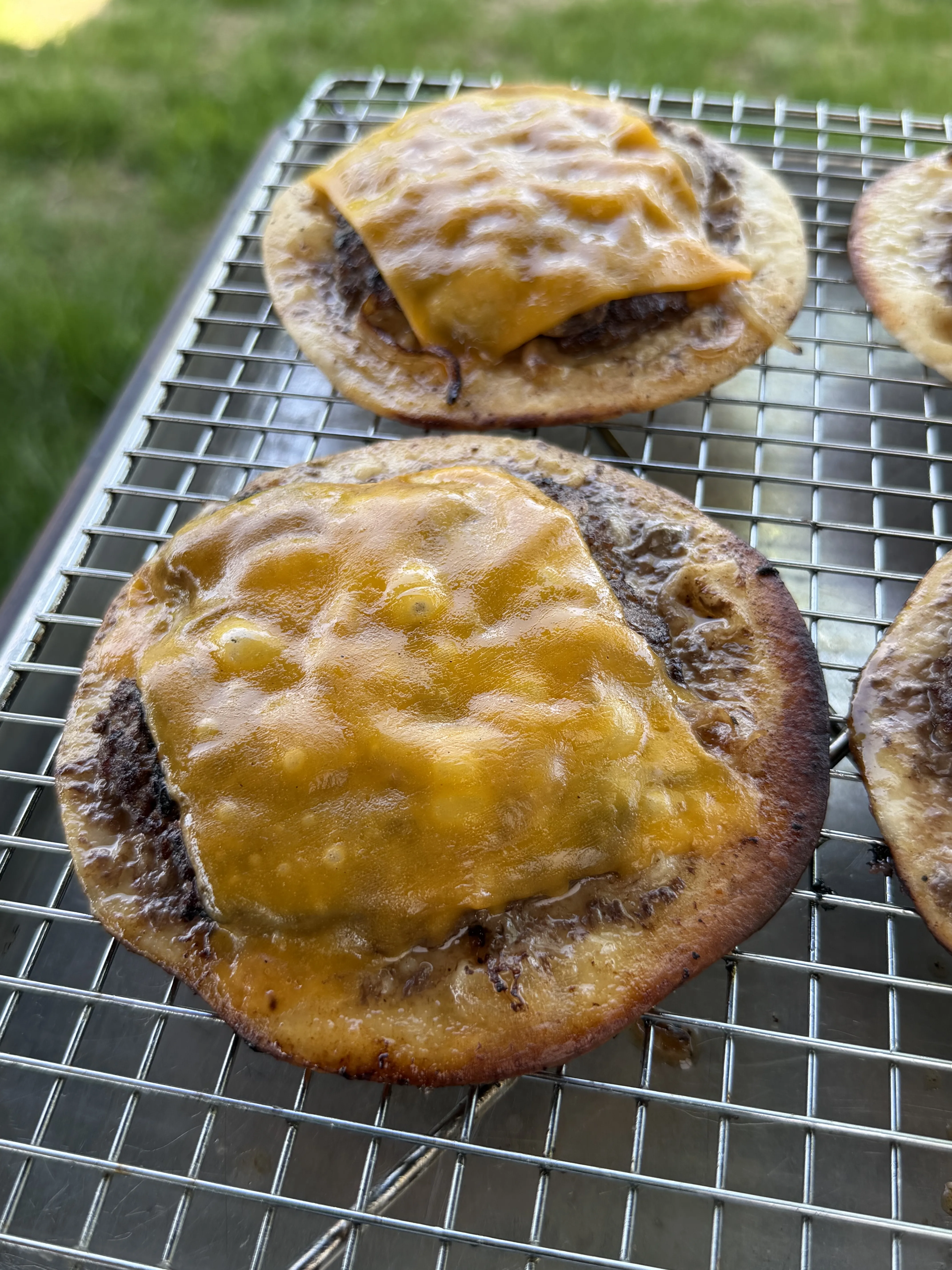 Oklahoma onion smash burger tacos with melted American cheese on the griddle