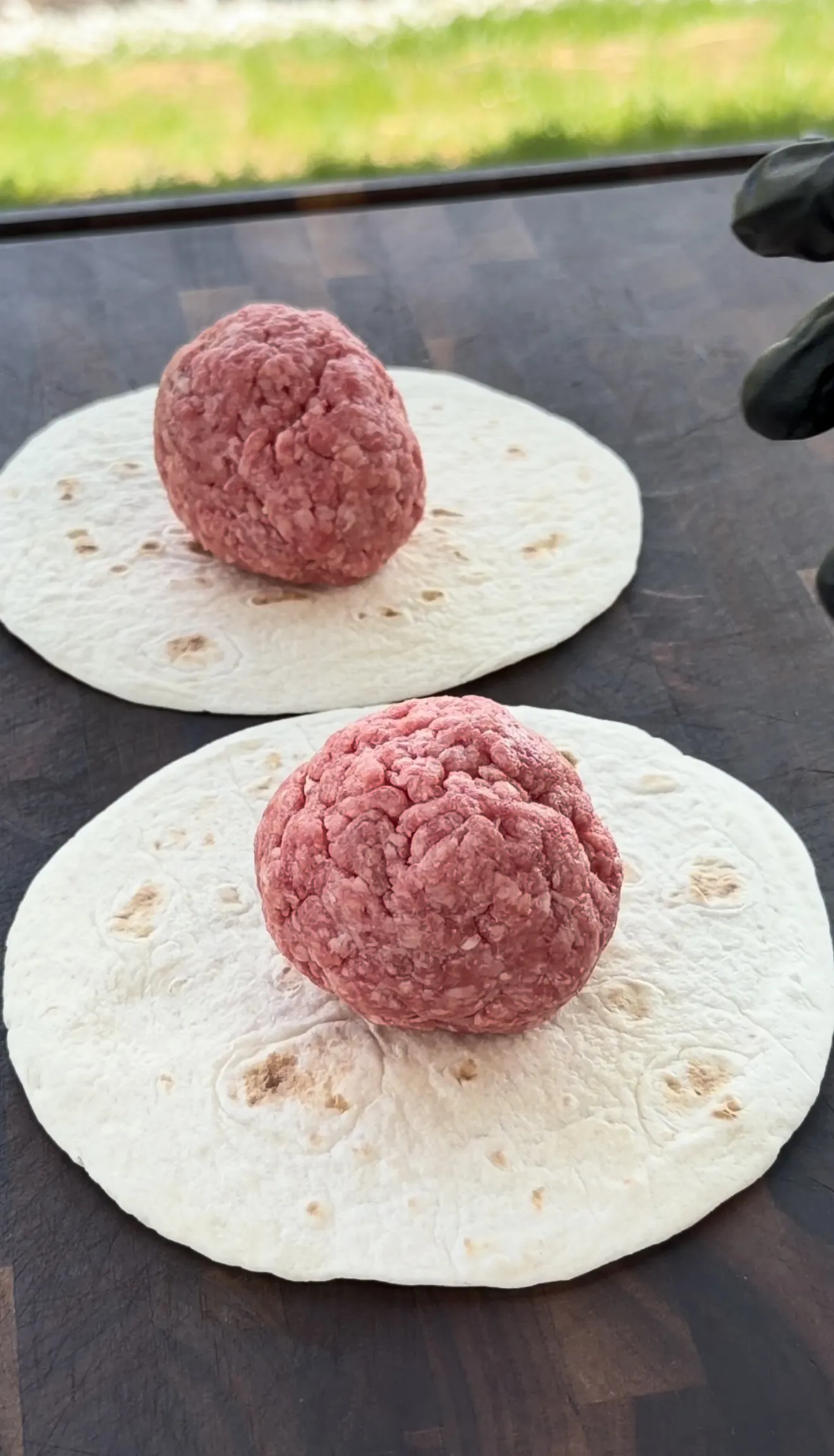 Raw 80/20 ground beef balls portioned next to street taco flour tortillas for smash burger tacos