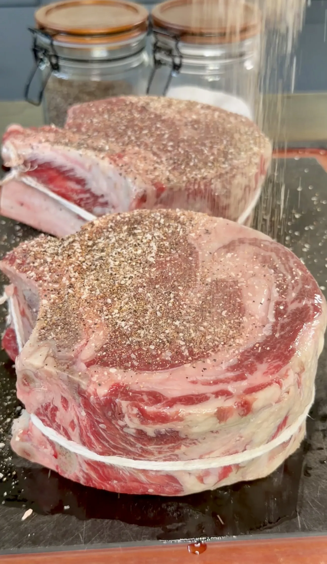 Close-up of raw ribeye steaks seasoned with pepper and spice rub