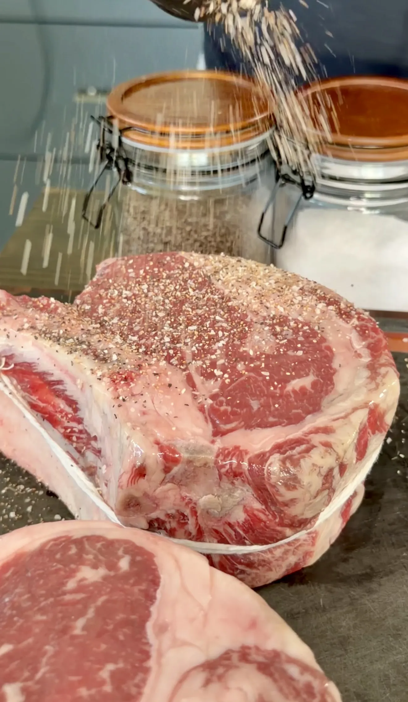 Raw ribeye steaks seasoned with salt and pepper ready for the grill