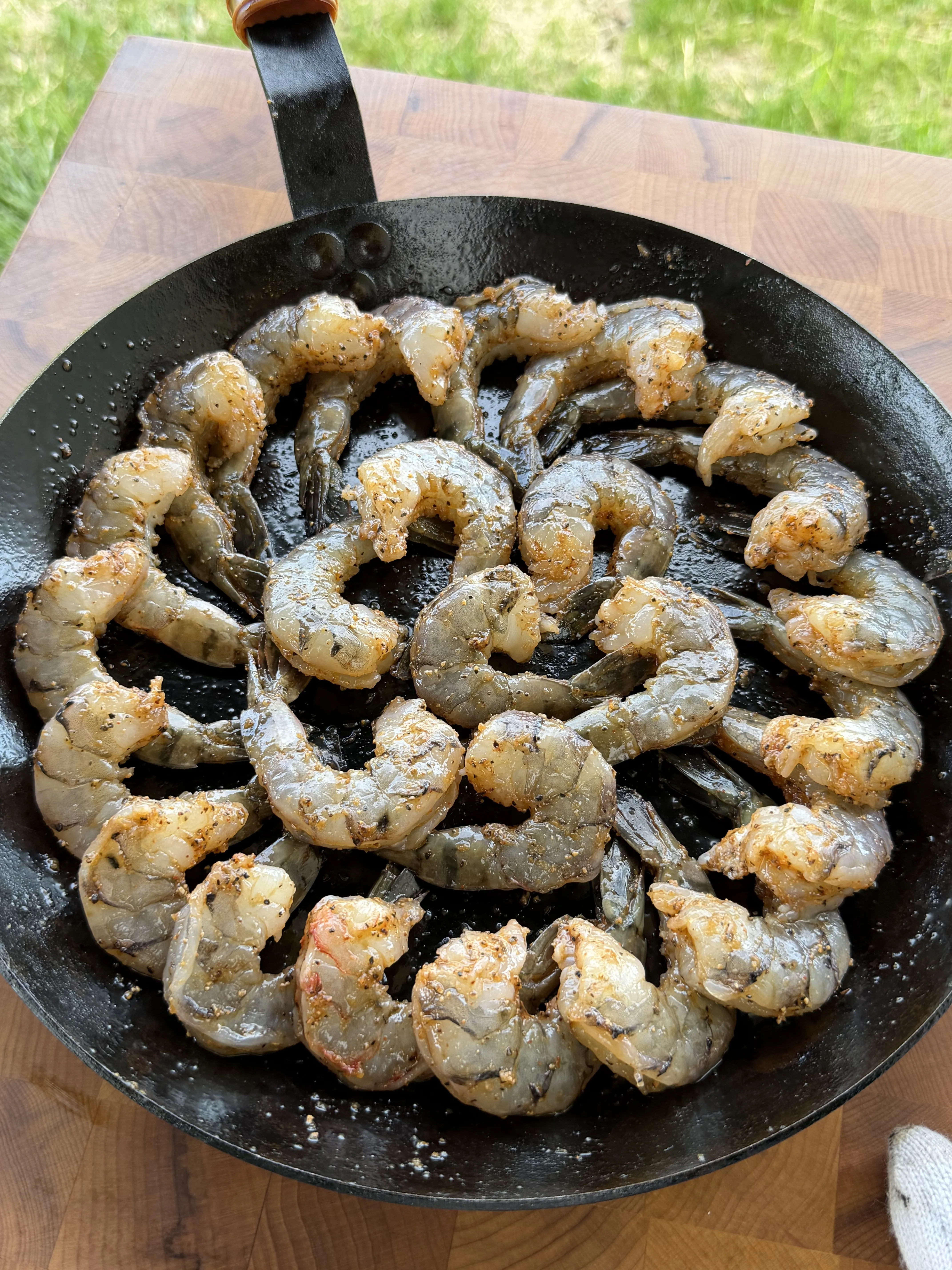 Seasoned raw shrimp arranged in a cast iron skillet before smoking