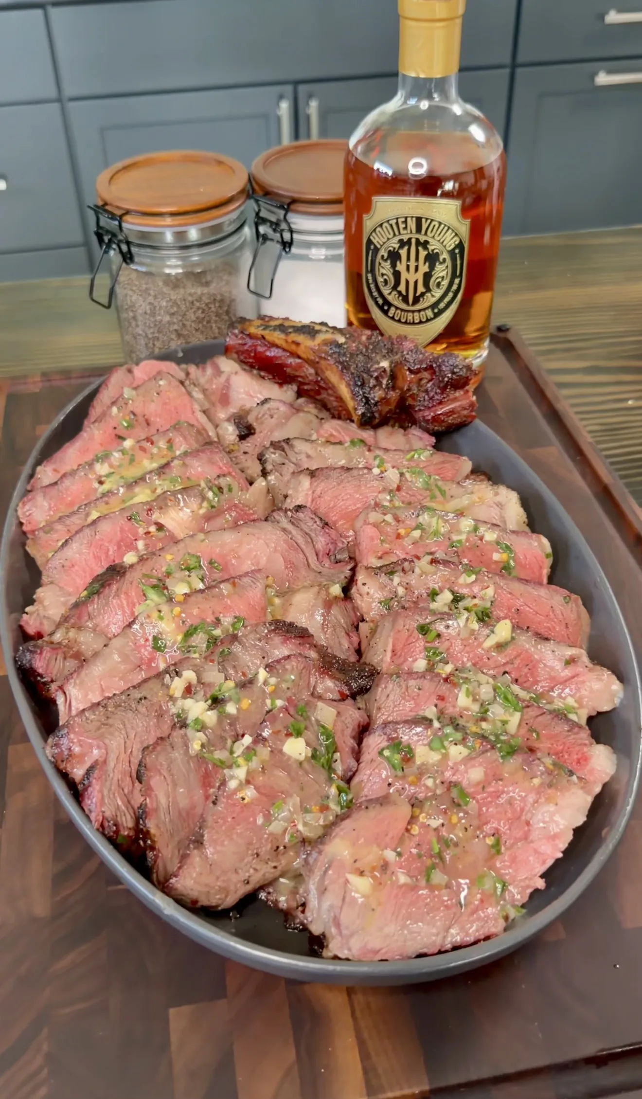 Sliced grilled steak with whiskey butter garnished on a serving platter
