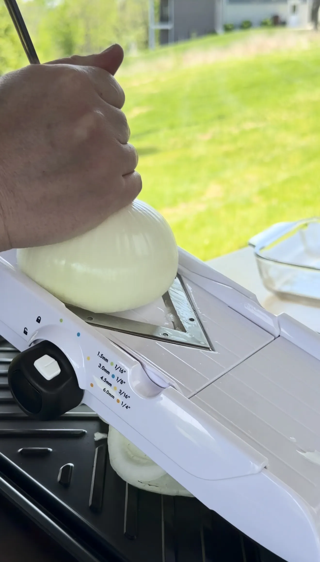 Slicing sweet onion paper-thin on a mandoline slicer for Oklahoma onion smash burger tacos
