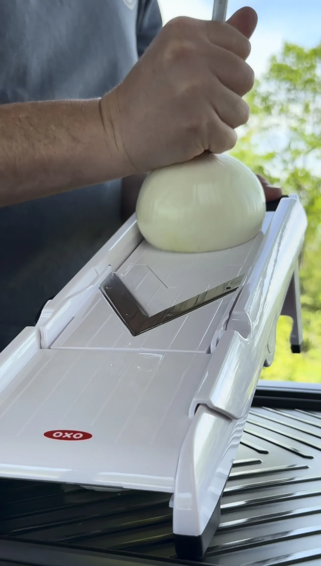 Mandoline slicer cutting paper-thin onions for Oklahoma onion smash burger tacos