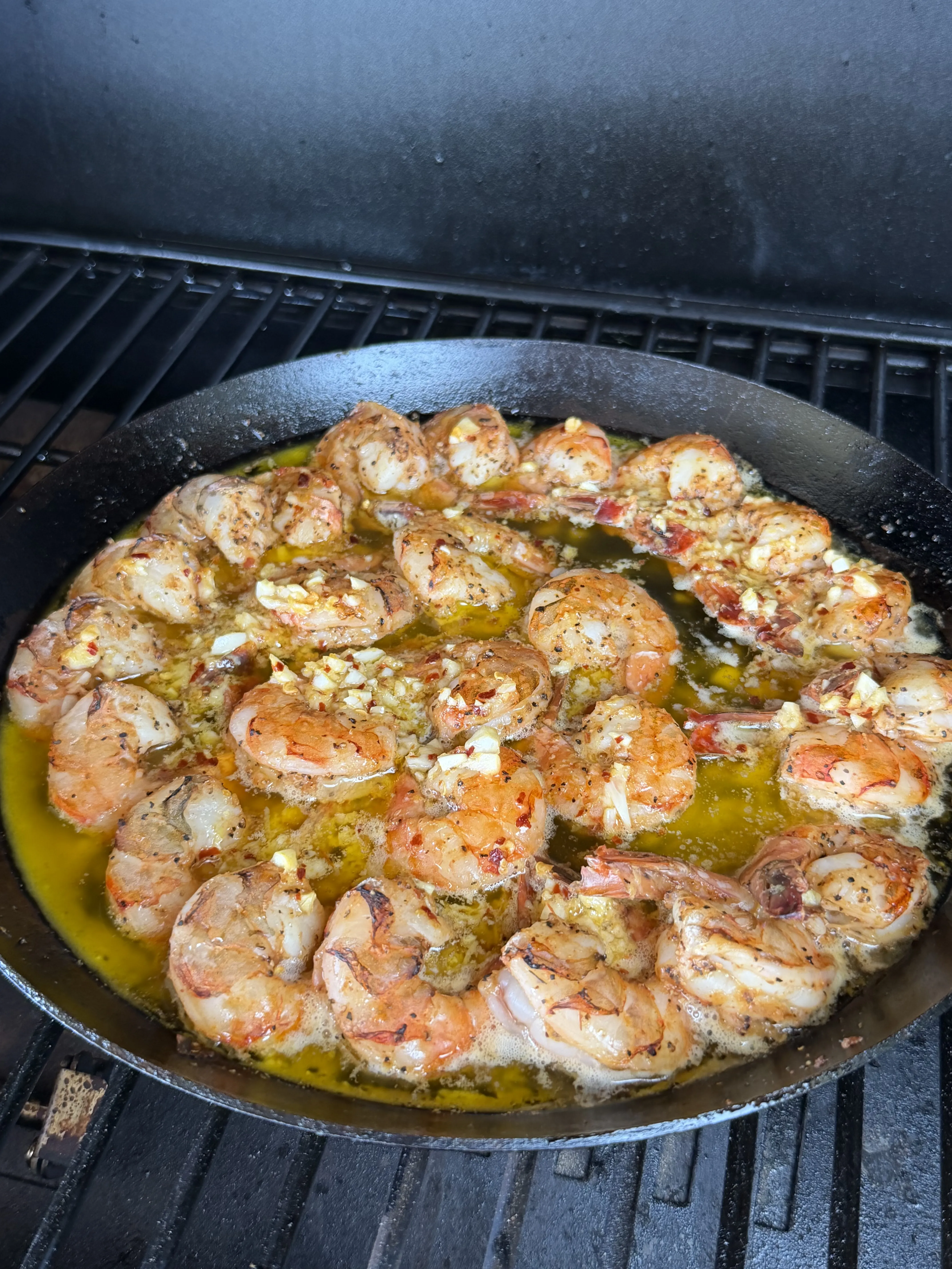 Finished smoked shrimp with garlic butter in a cast iron skillet