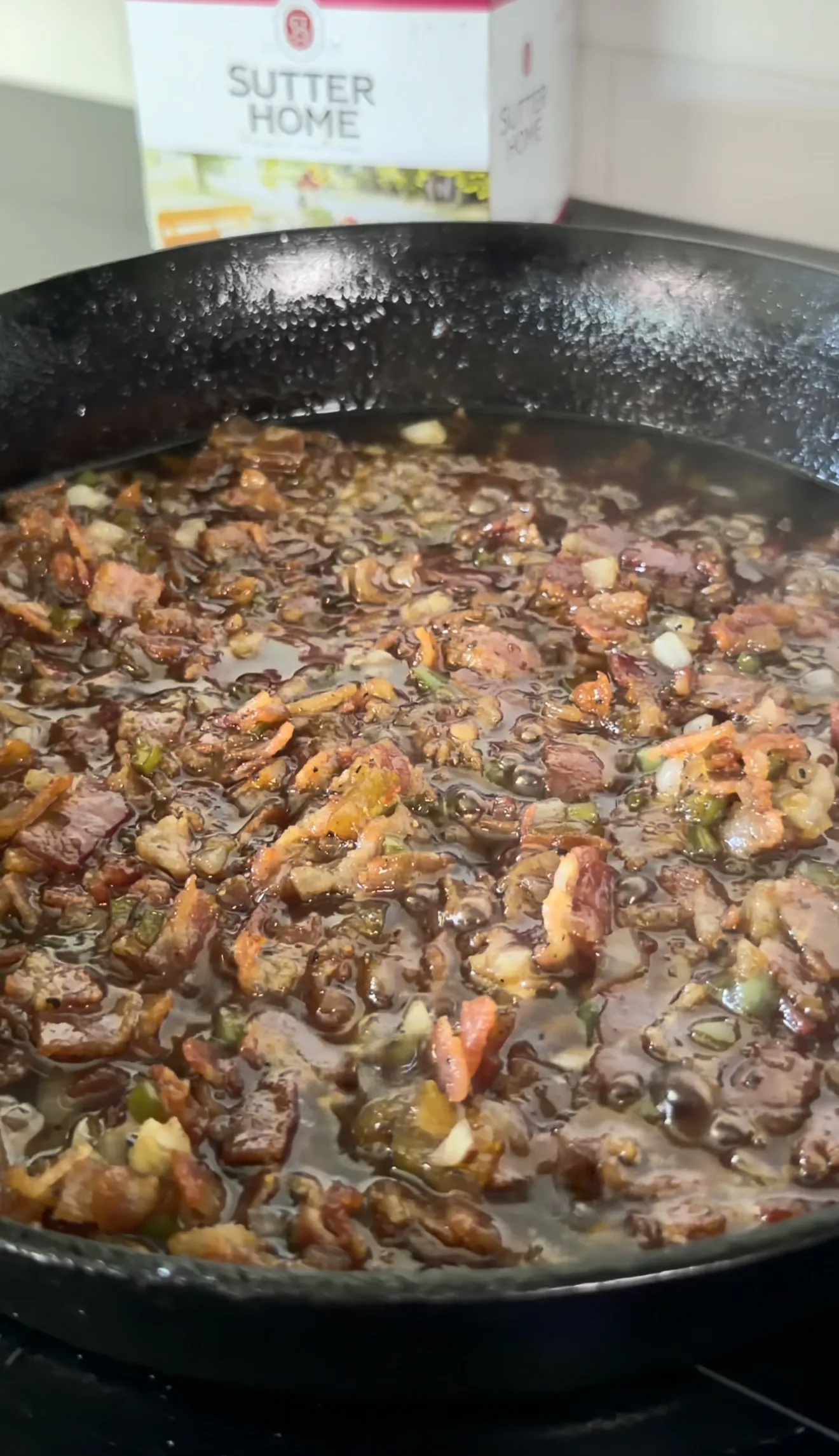 Bacon jam with caramelized onions and peppers simmering in a cast iron skillet