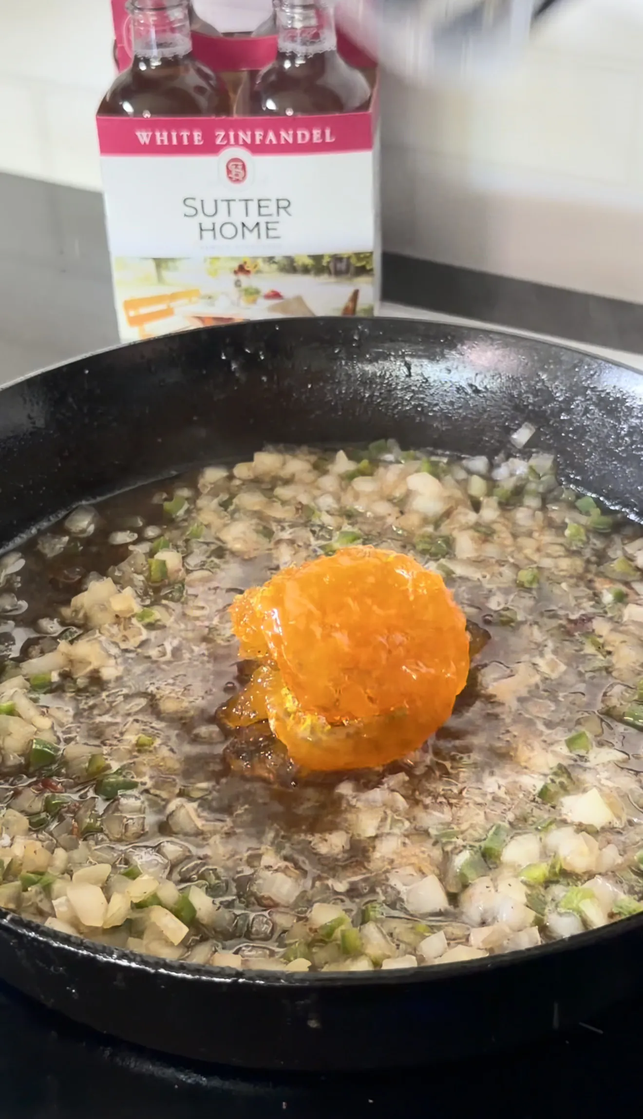 Bacon jam cooking in skillet with caramelized onions and white zinfandel
