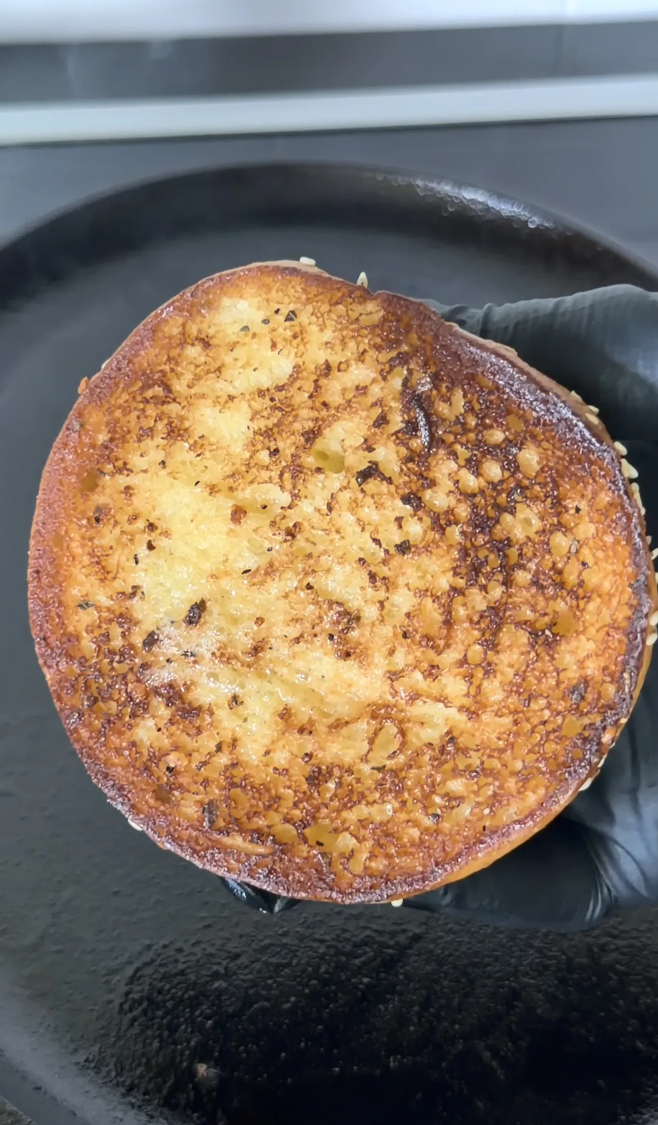 Golden brown bacon jam smash burger patty with caramelized edges in cast iron skillet